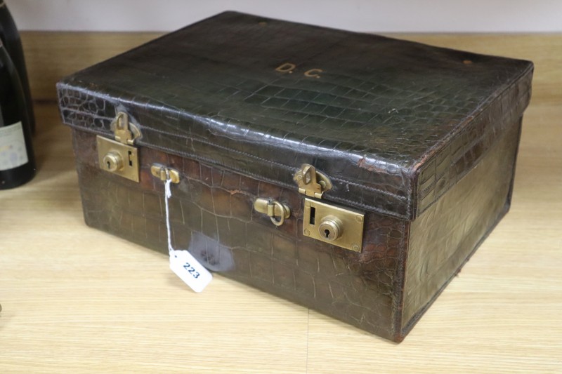 A crocodile skin travelling toilet case, containing silver topped glass jars,